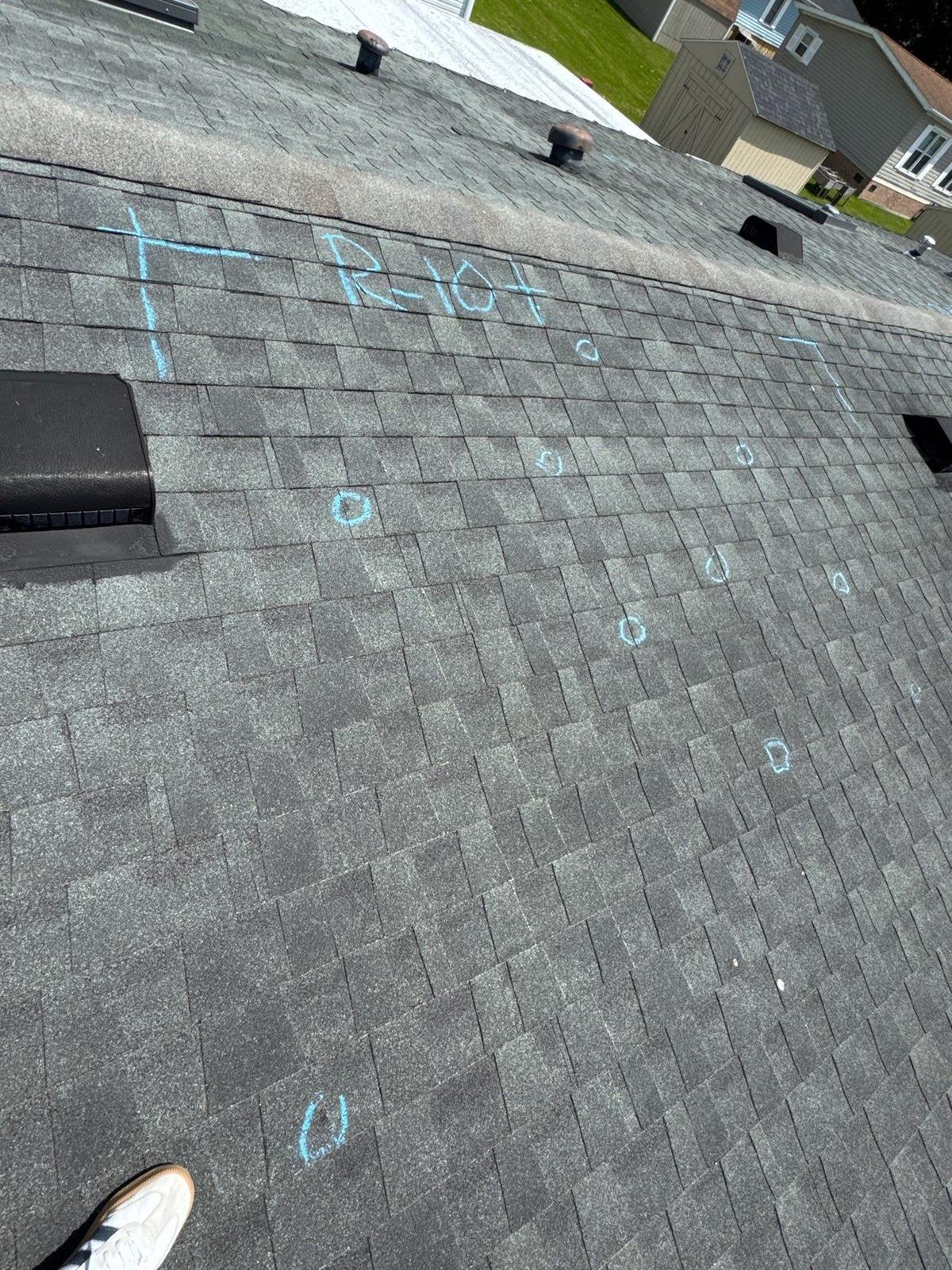 Hail damage inspection on a gray 3-tab shingle roof with blue chalk circles marking individual hail impacts inside a marked test square