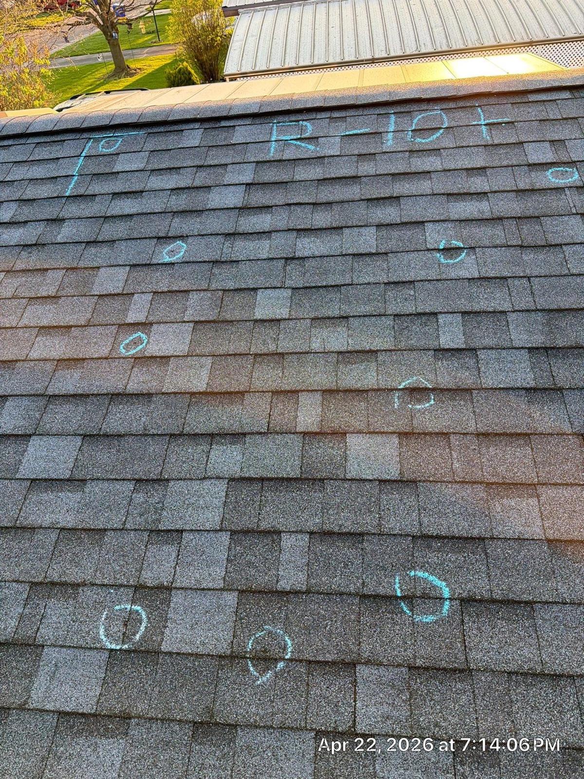 Blue chalk circles marking hail damage impact points on a residential asphalt shingle roof during a storm damage inspection