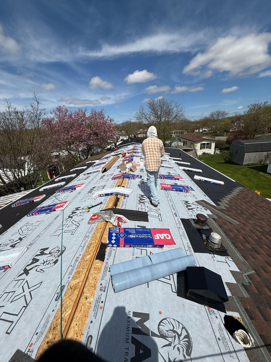 Eversafe Roofing crew member walking a roof papered with synthetic underlayment, GAF Timberline HDZ bundles staged along the ridge