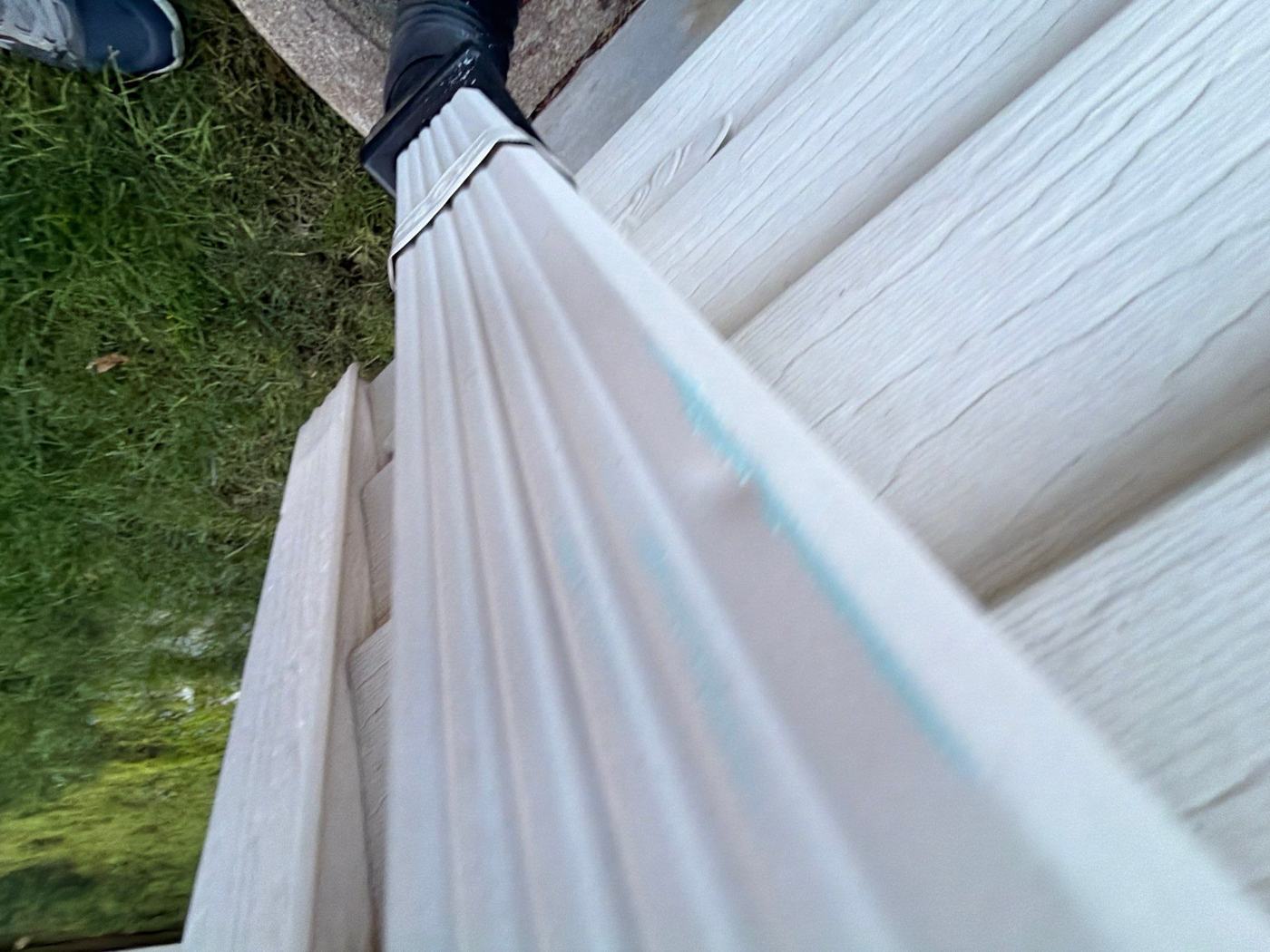 Downspout with a hail dent marked in blue chalk during an Eversafe roof inspection