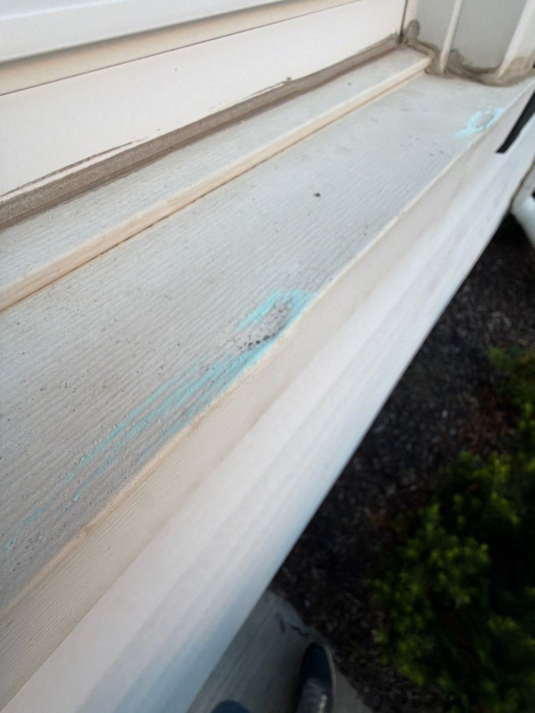 Chalk-marked hail dents along wrapped fascia metal above a gutter run