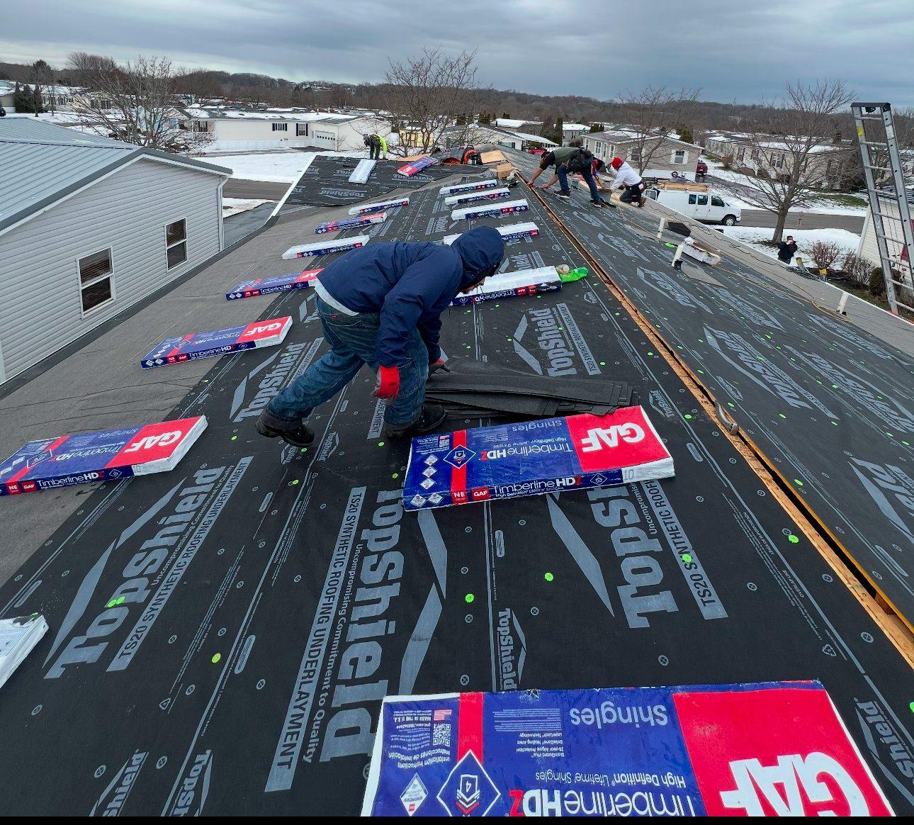 Eversafe Roofing crew installing GAF Timberline shingles on a snowy winter roof replacement