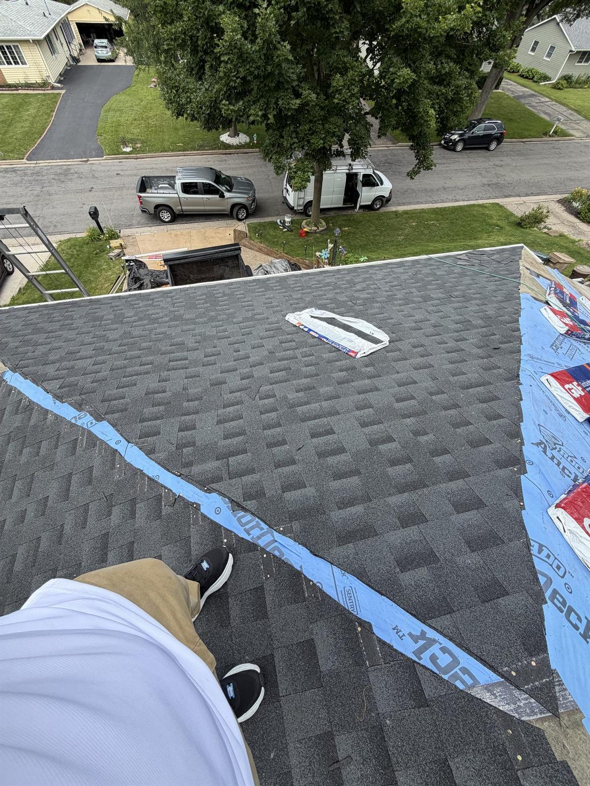 Newly installed charcoal architectural shingles on a residential roof nearing completion