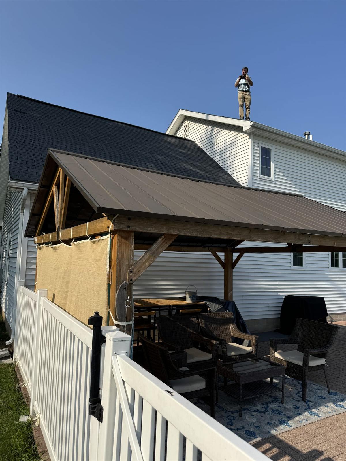 Backyard view of a home with a new charcoal architectural shingle roof above a covered pergola patio