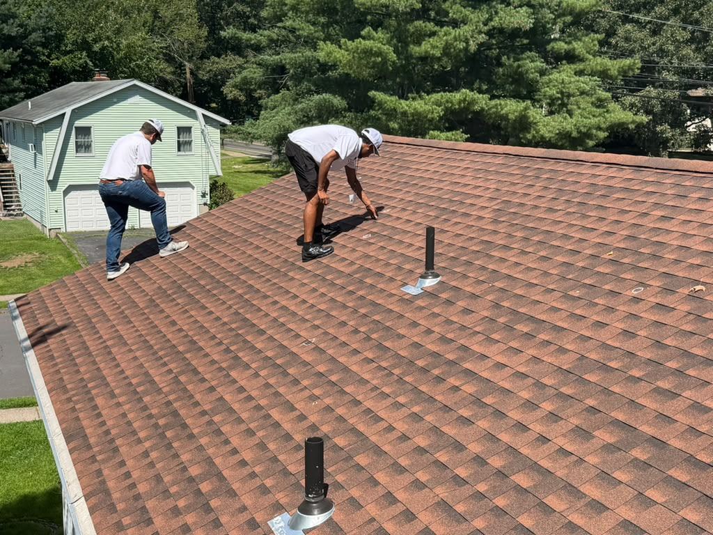 Two Eversafe Roofing inspectors on a residential roof, one marking a finding by hand during a documented inspection